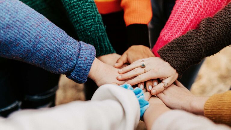 Group of friends in a circle with hands together.